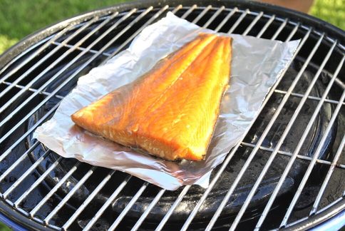 Halve warm gerookte zalm op aluminium folie op de barbecue bbq