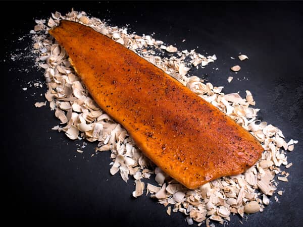 Gekruide warm gerookte zalm liggend op rookmot