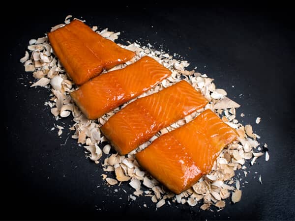 Warm gerookte zalm mootjes op rookmot en zwarte achtergrond