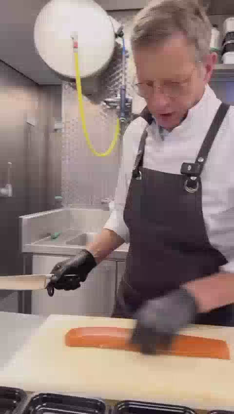 Video waarop een verse koud gerookte zalmhaas professioneel wordt gesneden voor servering.