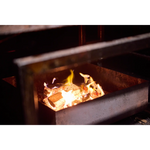 Houtvuur in de rokerij van Zalm van Urk tijdens het warm rookproces van zalm