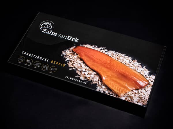 Geschenk verpakking met warm gerookte zalm erop op zwarte achtergrond